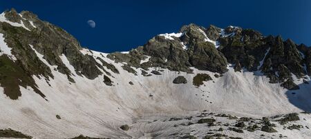 Moon rises over snow pass Zagedan lake. Caucasus mountains. Karachay-Cherkessia. Russia.の写真素材
