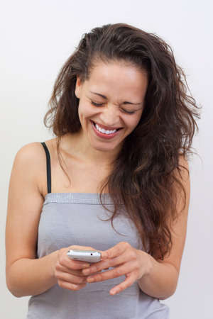 Happy young woman writing a message on her smartphone with a a big smileの写真素材