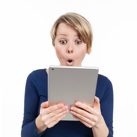 Young woman holding an electronic tablet and being astonished, isolated on whiteの写真素材