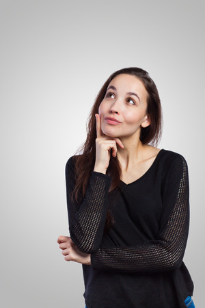 Young woman looking up at copy space, on grey backgroundの写真素材