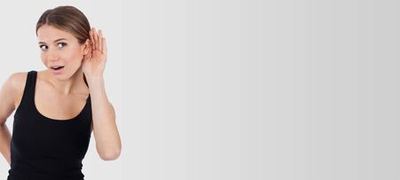 Woman curious trying to listen something, isolated on whiteの写真素材