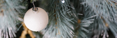 White Christmas bauble hanging on a silver and green Christmas Tree