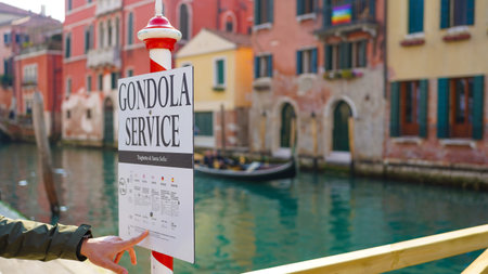A person pointing at a gondola service sign in Veniceの写真素材
