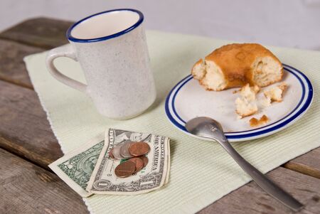 Cup of Coffee and a donut on a picnic table with a tip for the waitress or waiterの写真素材