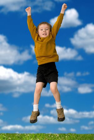 Young attractive boy jumps on a hill with a sky backgroundの写真素材