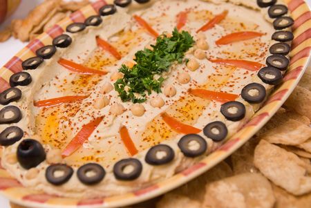 Hummus with toasted pita bread on a yellow and red stripped plate