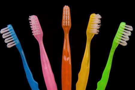 Brightly colored Toothbrushes side by side on a black background