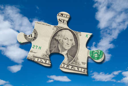 Puzzle piece of money floating in a cloudy skyの写真素材