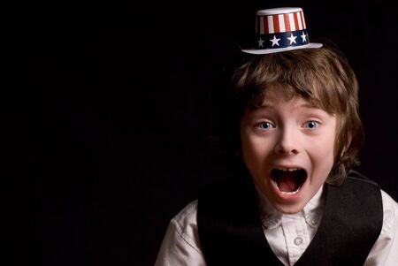 attractive young boy up-close and surprised with a patriotic american hat isolated over a black background                                の写真素材