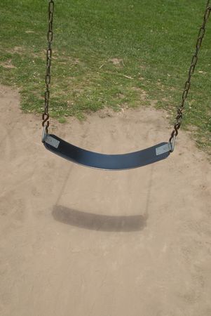 Swing on a chain over dirt and grass on a sunny day