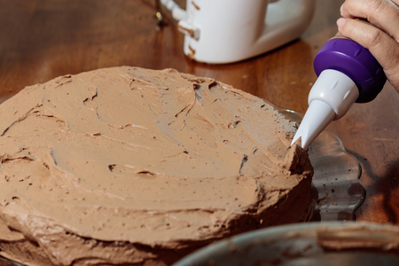 piping chocolate frosting onto cakeの写真素材