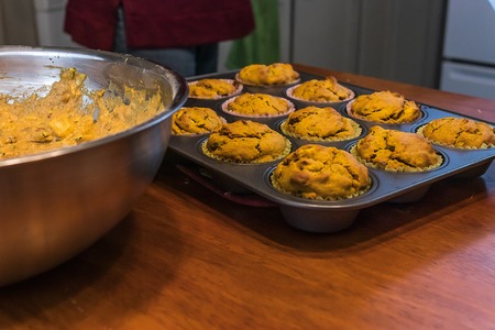 homemade muffins in a muffin tray near a bowl with muffin batterの写真素材