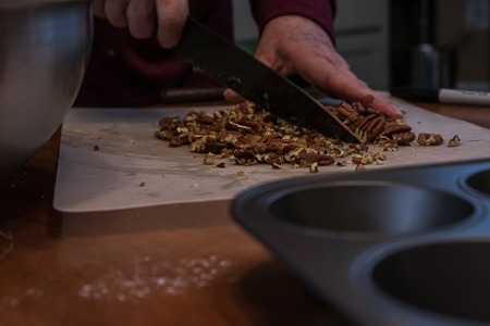 a pile of pecans being chopped with a knifeの写真素材