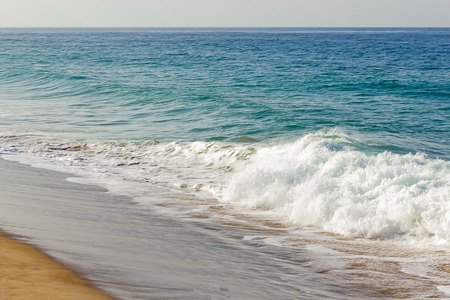 foaming fading wave on sandy shoreline, wave cresting, foaming backwash,の写真素材