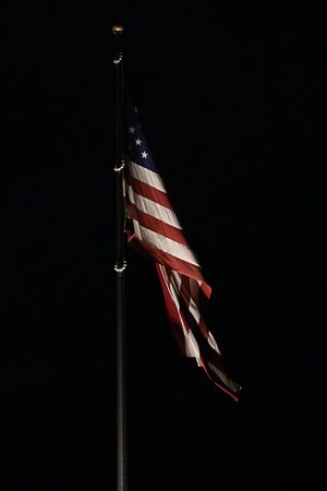 bright american flag flapping and flying high in nightの写真素材