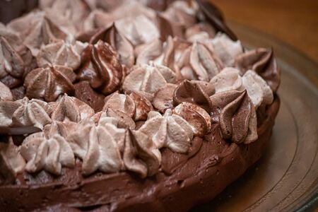 varigated frosting swirled on top of a thin single layer coffee flavored cake on a platter set on a table in a kitchenの写真素材