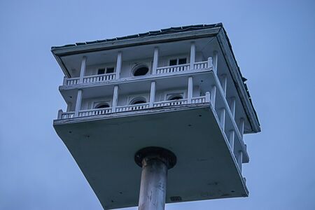 an old hand crafted birdhouse with pilars a wrap around deck and roof on a poleの写真素材
