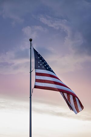 american flag flying high in cloudy sky during spring against blue and pinkの写真素材