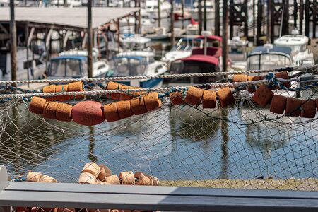 fishing net with bouys hang in front of harbor town