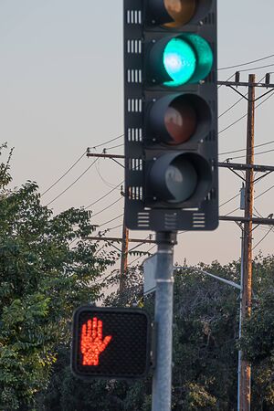 a traffic light on green indicatiing go, and pedestrian walk light red