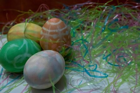 colorful dyed easter eggs gathered on a table with easter grass