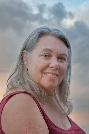 mature older woman with gray hair smiling against natural background