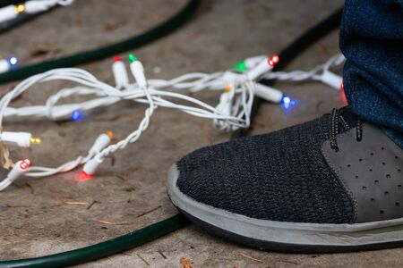 mans shoe standing over cords and strings of lights at christmasの写真素材