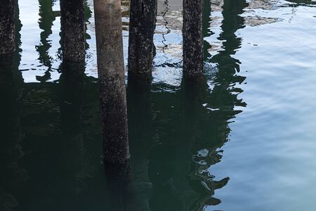 dock pilons reflected in the water on a cloudy day