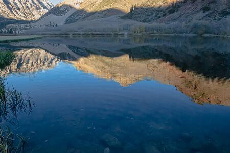 bright blue still lake surface reflecting surrounding mountain range