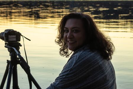 smiling woman with camera looking out over water