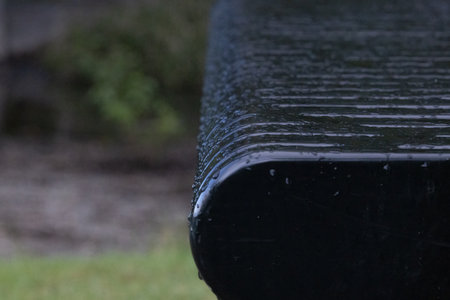 dark black shiny park bench in the rainの写真素材