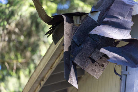 scrapped off shingles hanging from gutters on roof