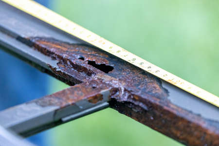 measuring corroded metal frame with rusty holeの写真素材