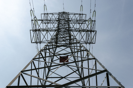 a high voltage power pylons against blue sky and sun rays