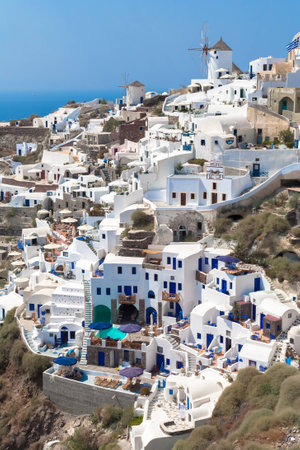 Old-style white traditional windmills in terraced village Oia of Cyclades island Santorini Greece on the blue Aegean Sea and sky backgroundの写真素材