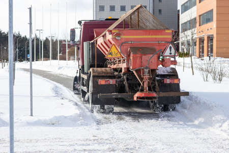 A large orange snowplow cleans snow from the pavement.の写真素材