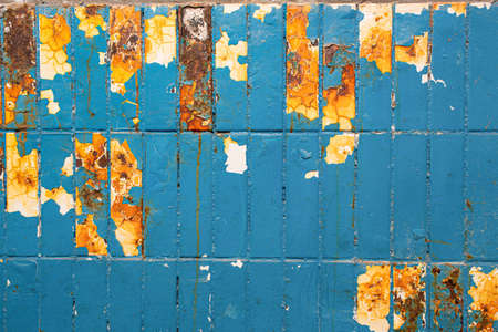 Colorful old industrial background. Dirty blue cracked paint with chunks of flaking, and underneath, white tiles with orange rusty streaks and acid stains.の写真素材