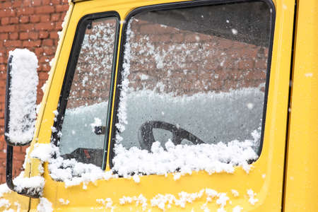 Bright yellow truck cab in bad weather. The glass of the truck cab is covered with snow.の写真素材