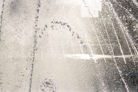 Jets and flying splashes of water of the city fountain on a bright sunny summer dayの写真素材