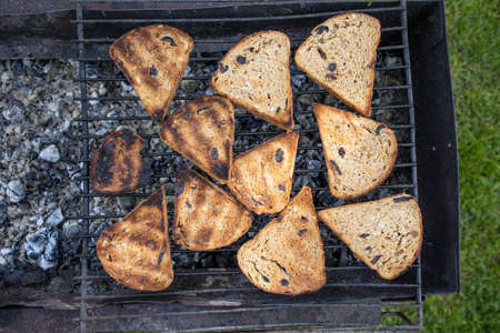 Appetizing slices of bread are browned on a charcoal grill.
