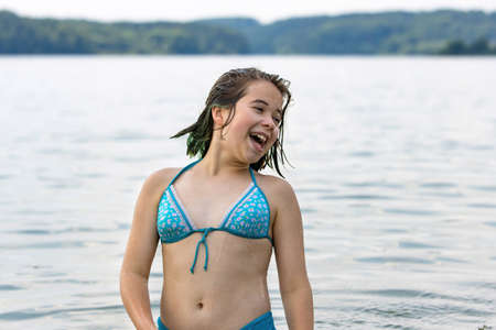 A teenage girl in a blue swimsuit enjoys swimming in the warm calm lake waterの写真素材