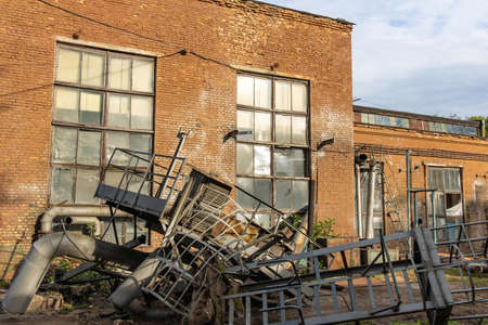 The territory of an old abandoned factory littered with dismantled metal structures. Dangerous place in an neglected plantの写真素材