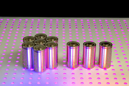 New modern lithium-ion batteries with increased capacity. A prototype of new batteries on a laboratory table illuminated by an ultraviolet lamp.の写真素材