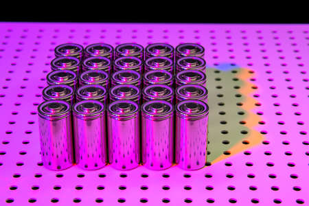 New modern lithium-ion batteries with increased capacity. A prototype of new batteries on a laboratory table illuminated by an ultraviolet lamp.の写真素材