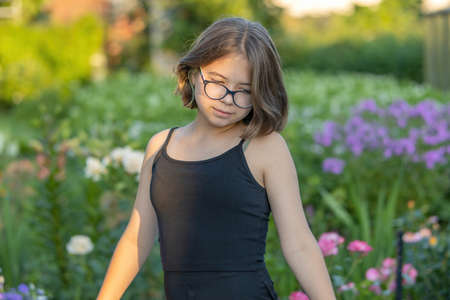 Portrait of a girl with glasses in black clothes in a blooming evening summer gardenの写真素材