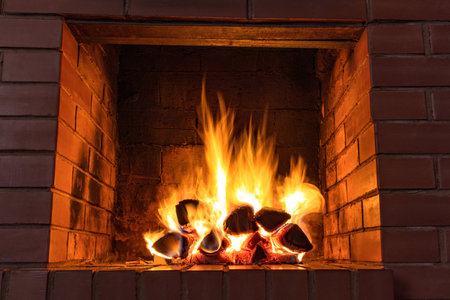 Burning logs in a red brick fireplace in a country cottageの写真素材