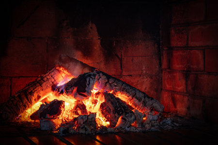 Close-up of a pile of burning firewood and bright coals in a red brick fireplaceの写真素材