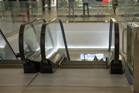 A deserted escalator fenced with a glass fence in a shopping center leads to the lower floorの写真素材