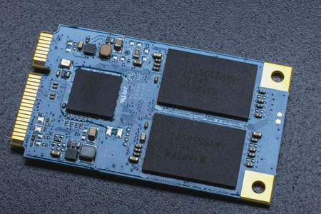 M.2 format SSD module. Close-up of an electronic circuit board with gold-plated contacts and memory chipsの写真素材