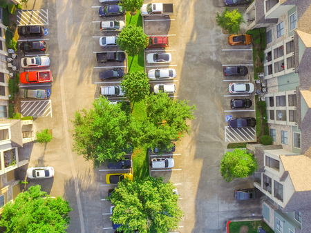 Aerial view of apartment garage with full of covered parking, cars and green trees of multi-floor residential buildings in Houston, Texas, US at sunset.の写真素材